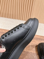 Black leather sneaker side view with perforations, stitching, and chunky sole