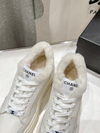Close-up of white lace-up sneakers with faux-fur collar and Chanel logo on tongue