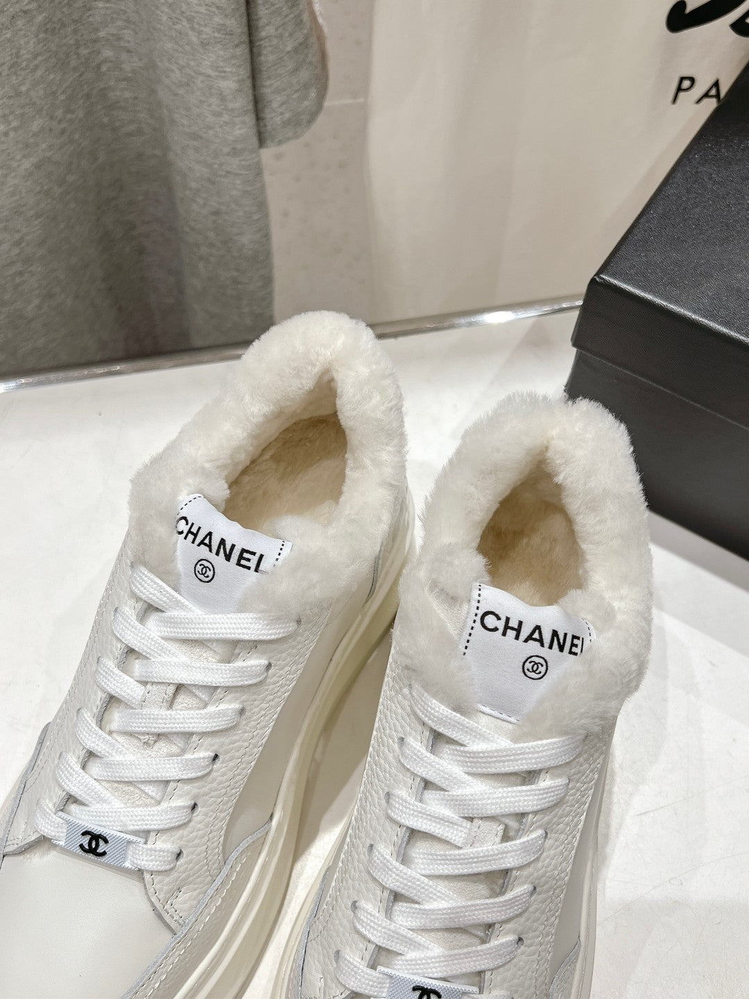 Close-up of white lace-up sneakers with faux-fur collar and Chanel logo on tongue