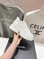 White lace-up sneakers with fuzzy collar and Chanel logo, side profile on display