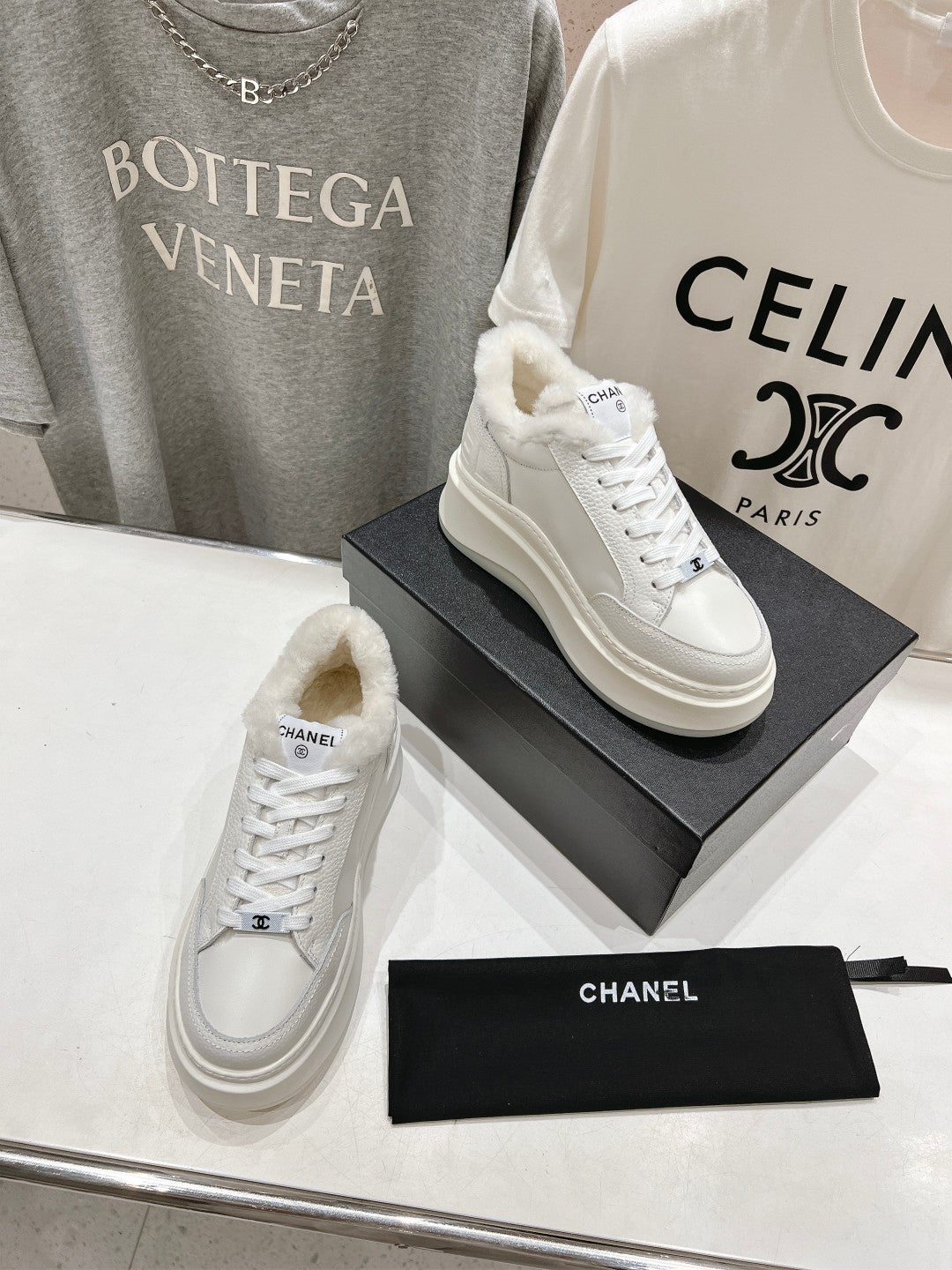 White lace-up sneakers with faux-fur lining collar and Chanel logo, two shoes on boxes