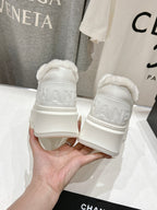 Back view of white lace-up sneakers with faux-fur collar and Chanel logo patch
