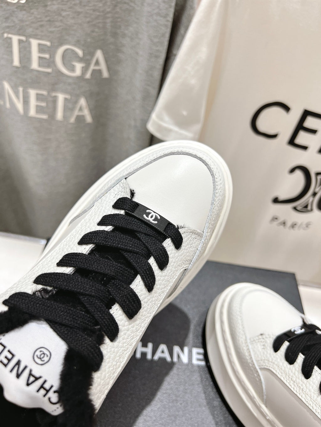 White sneaker toe close-up with black laces and black faux-fur collar detail