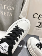 White sneaker toe close-up with black laces and black faux-fur collar detail