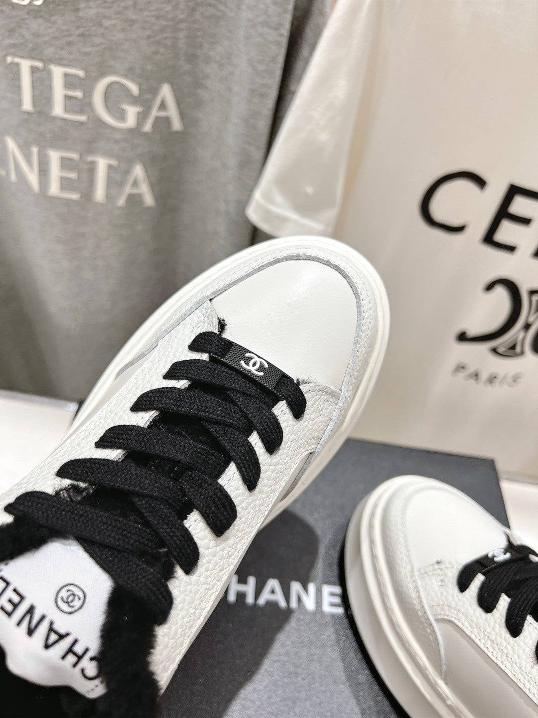 White sneaker toe close-up with black laces and black faux-fur collar detail