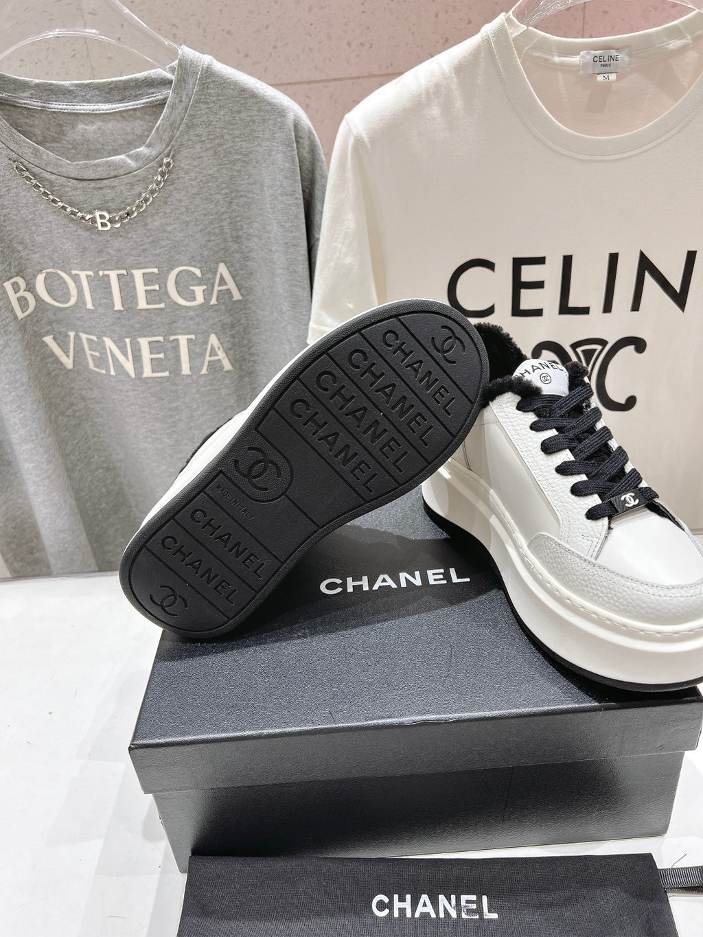 White sneaker with black outsole and Chanel branding, featuring black lace-up front