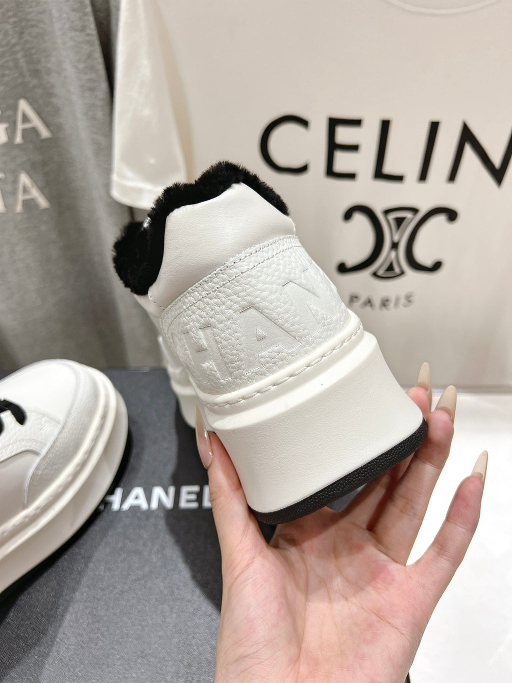 White sneaker heel with black faux-fur collar held in hand on a shoebox