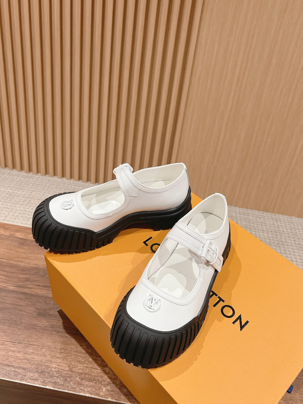 White sneakers with side strap detail and black ridged rubber soles