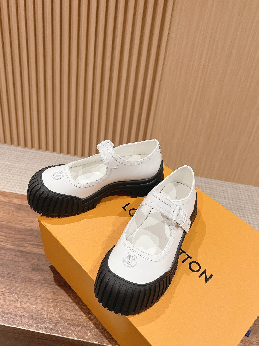 White sneakers with side strap detail and black ridged rubber soles