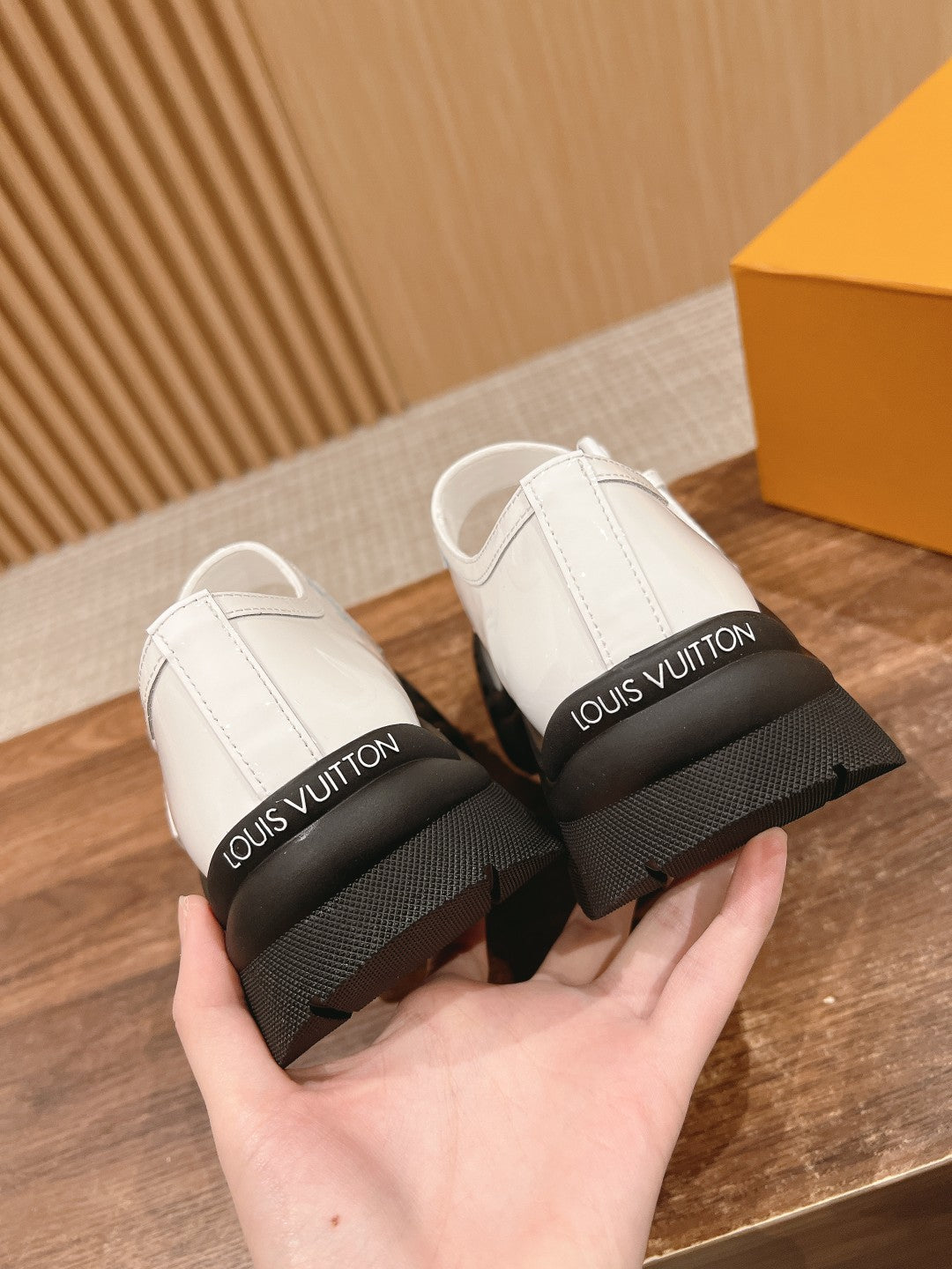 White sneakers with Velcro strap and black rubber soles, boxed for storage