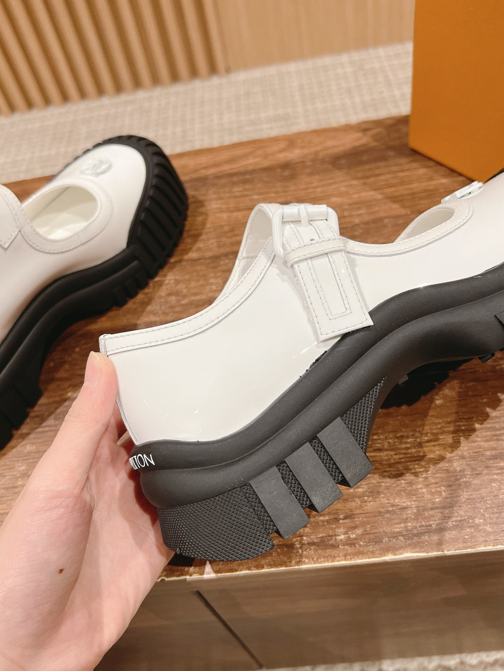 White sneaker showing front strap, chunky black sole with textured tread