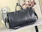 Louis Vuitton duffel bag with smooth black leather and top handles, side view.