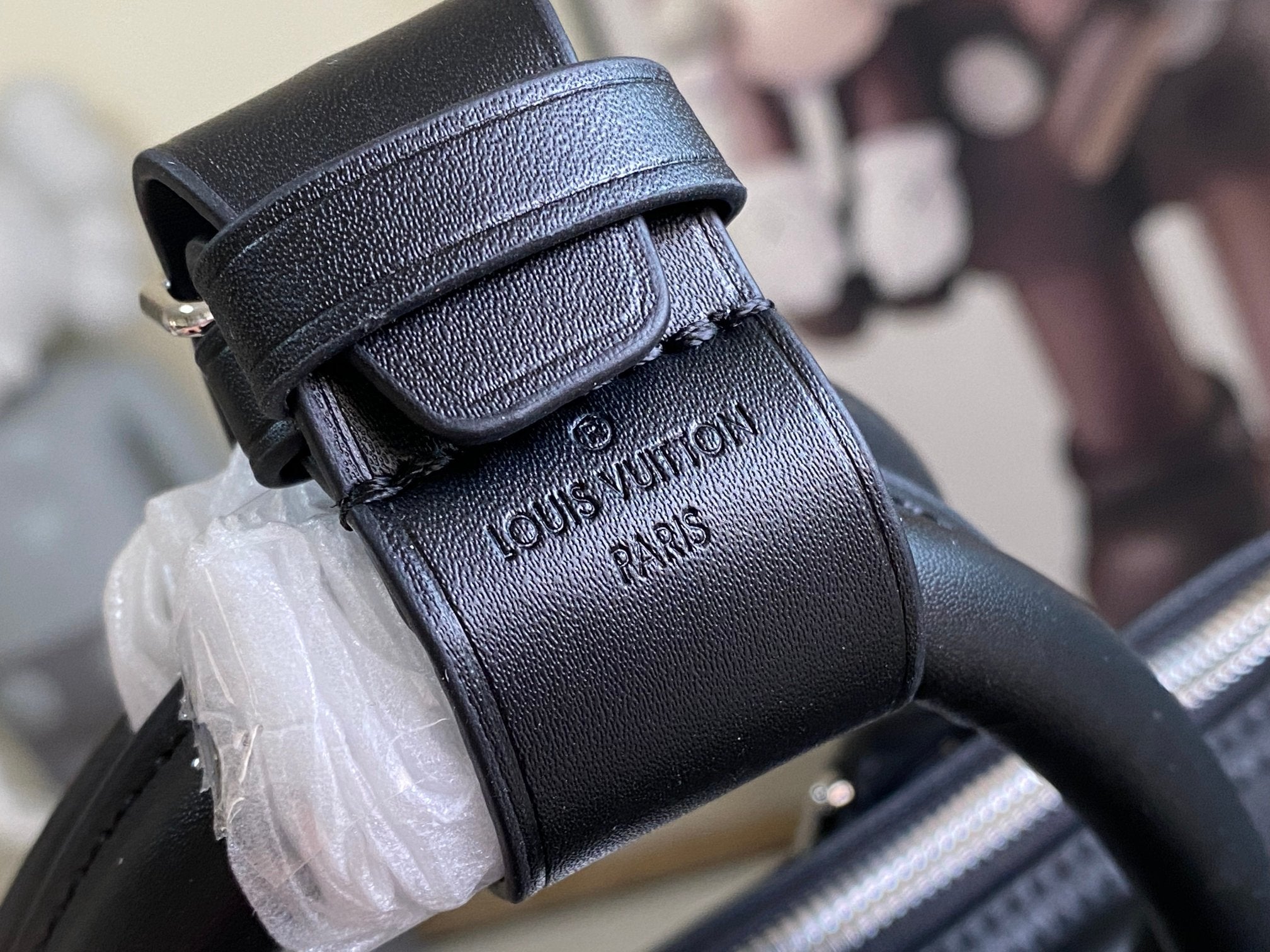 Louis Vuitton men’s leather bag with stamped branding and textured strap detail