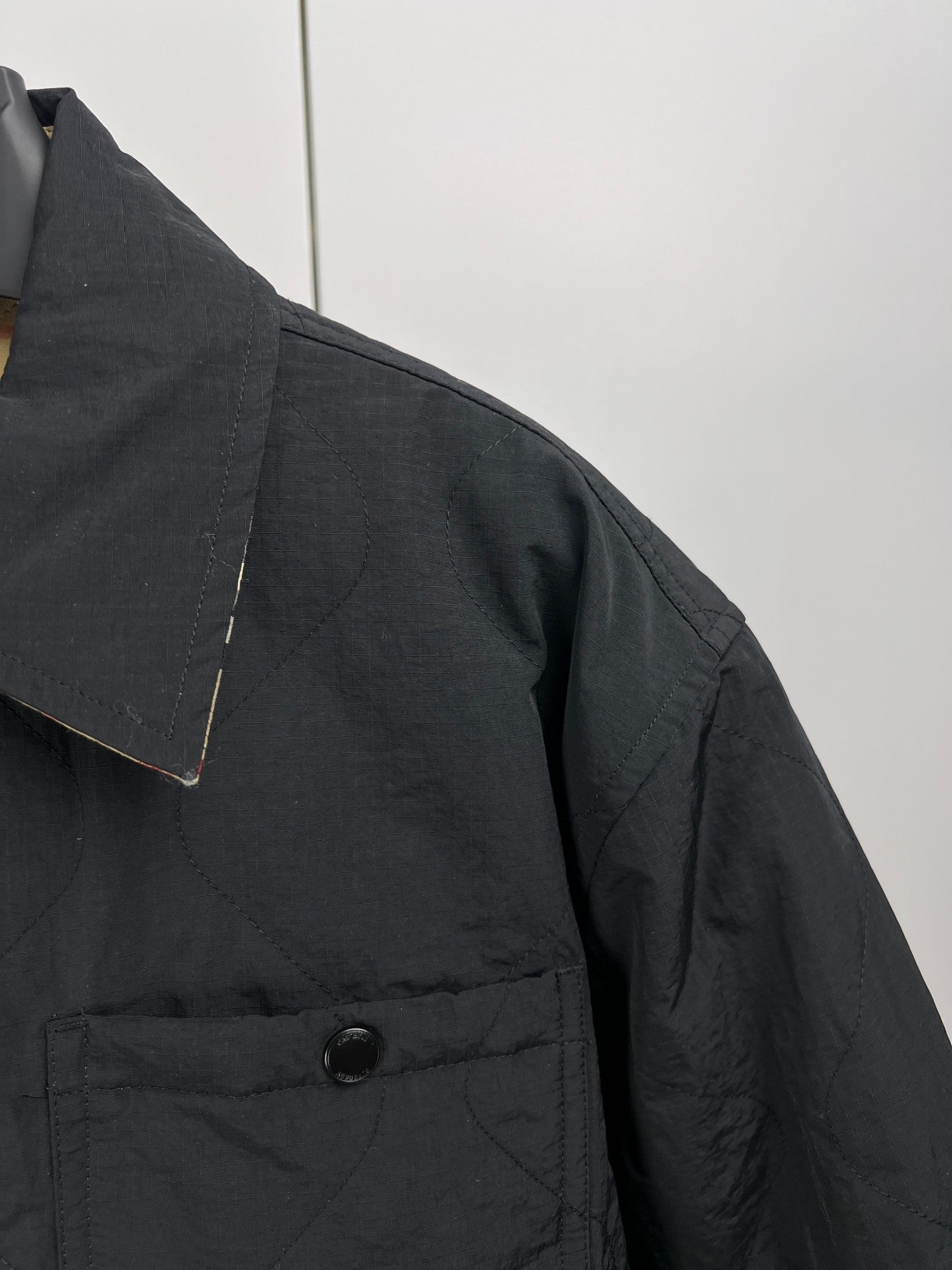 Quilted jacket shoulder and chest, dark outer fabric with buttoned front placket
