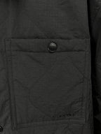 Quilted jacket pocket detail with round button on dark outer fabric