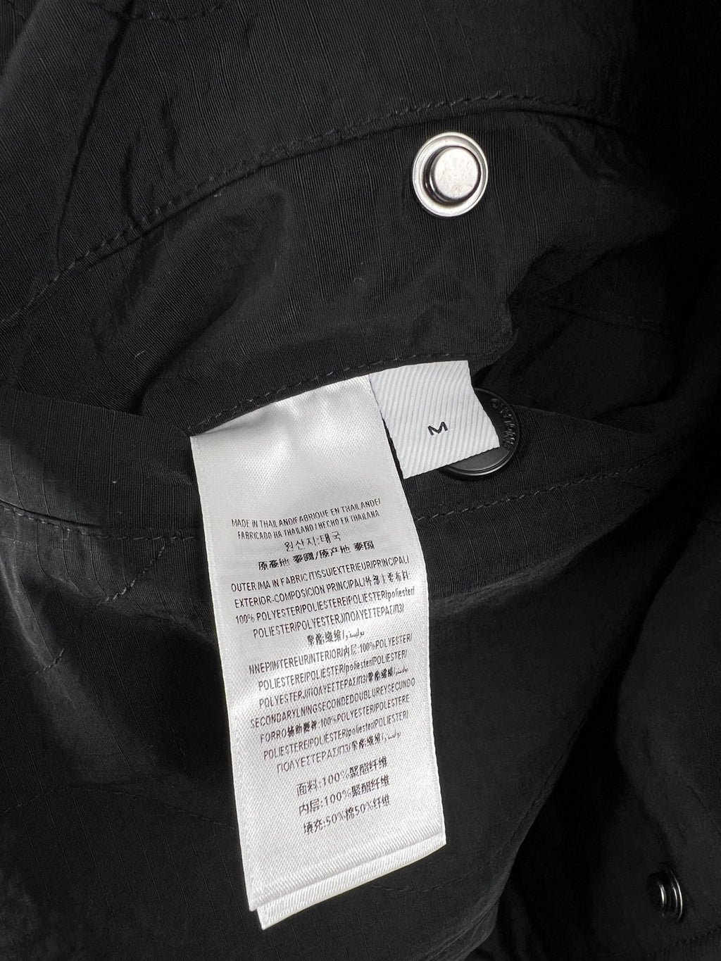Quilted jacket interior label area on dark outer fabric with metal grommet