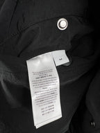 Quilted jacket interior label area on dark outer fabric with metal grommet