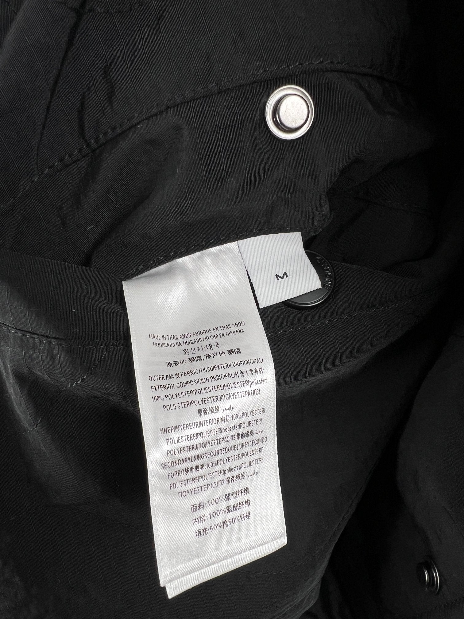 Quilted jacket interior label area on dark outer fabric with metal grommet