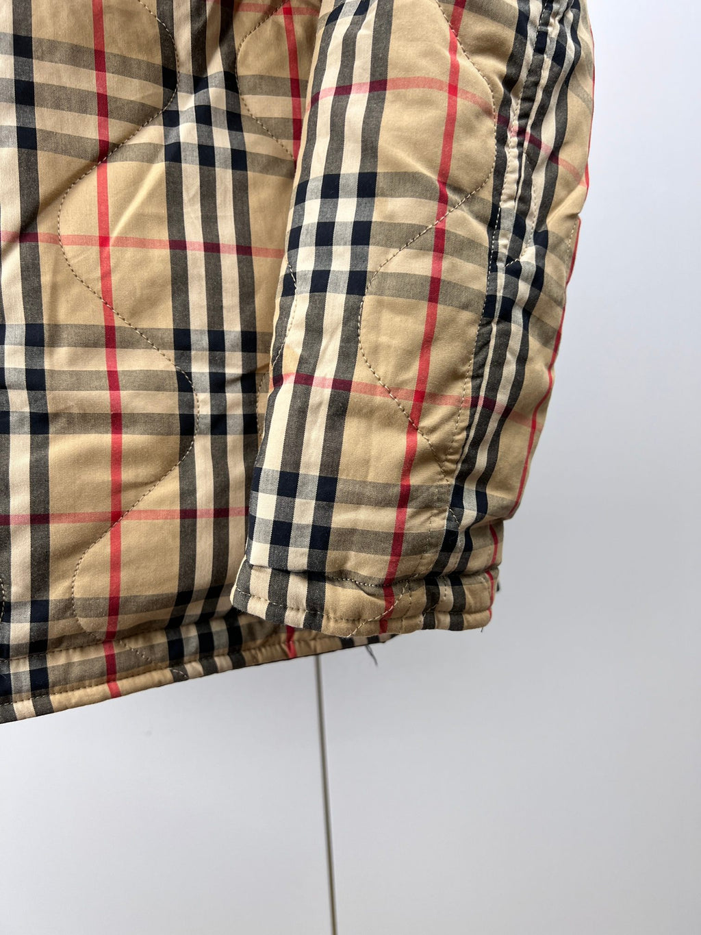 Plaid puffer jacket sleeve with elastic cuff and quilted seams