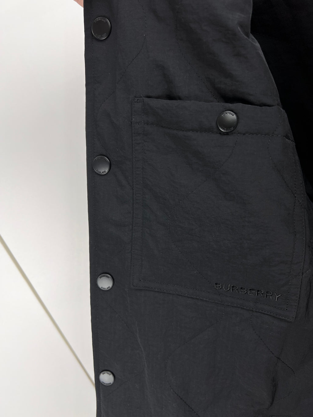 Black long jacket front with snap closures and buttoned pocket panel
