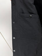 Black long jacket front with snap closures and buttoned pocket panel