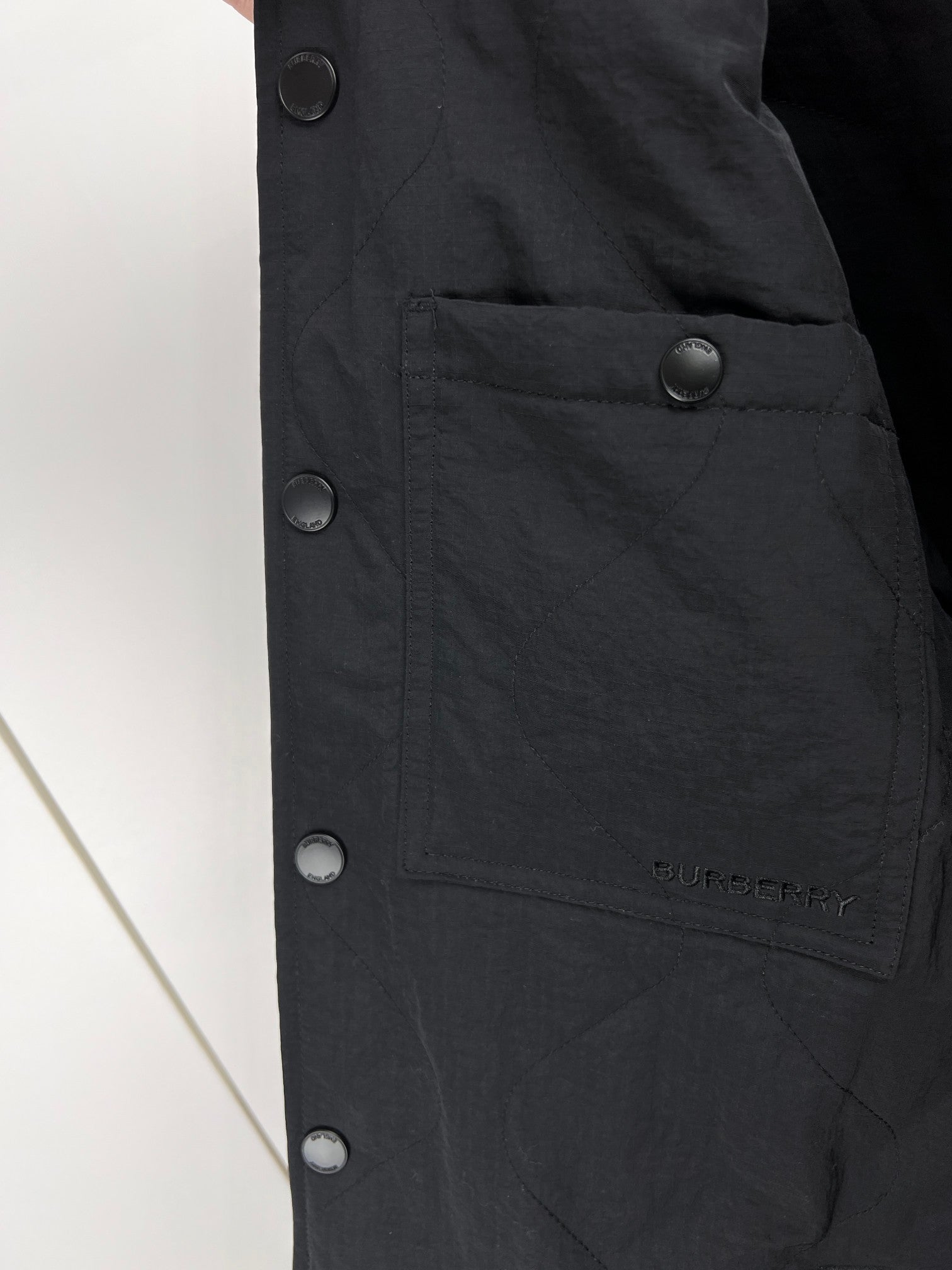 Black long jacket front with snap closures and buttoned pocket panel