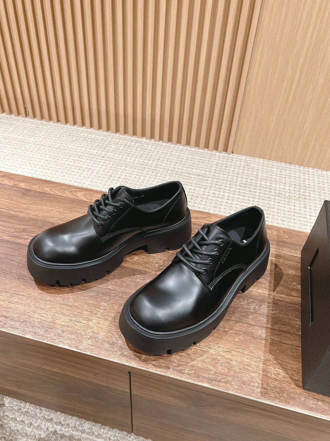 Black lace-up leather shoes with stitched panels and chunky rubber sole