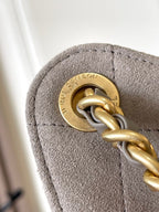 Gold-tone chain clasp hardware on gray suede-like fabric bag flap