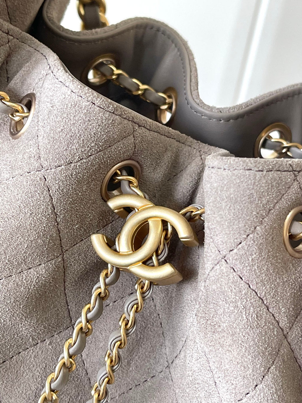 Gray quilted bag close-up with gold-tone O-ring and chain strap hardware