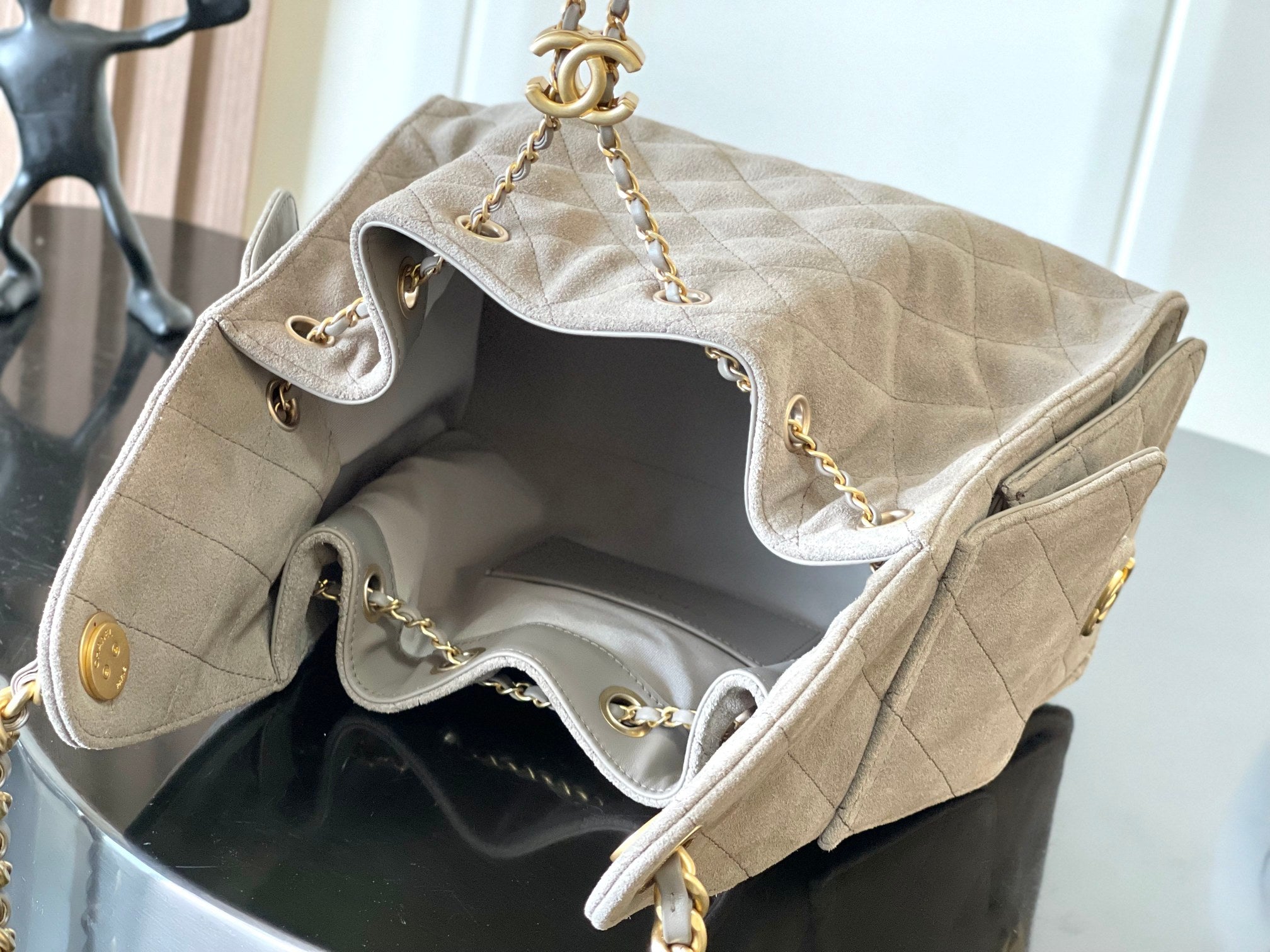 Open light gray quilted bag interior with gold-tone chain straps and hardware