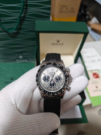 Rolex watch with black dial and chronograph subdials, black leather strap.