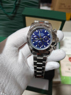 Rolex watch with blue dial and metal link bracelet, stainless steel chronograph.
