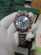 Rolex wrist watch with blue dial, orange accents, and metal bracelet