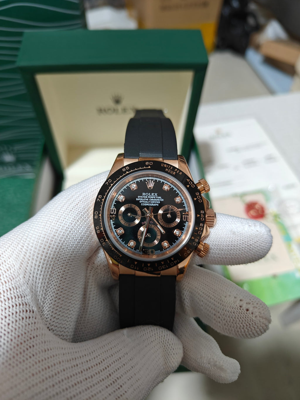 Rolex chronograph watch with black leather strap, rose-gold bezel, dark dial and three registers