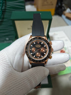 Rolex chronograph watch with black leather strap, rose-gold case, dark dial and multiple subdials
