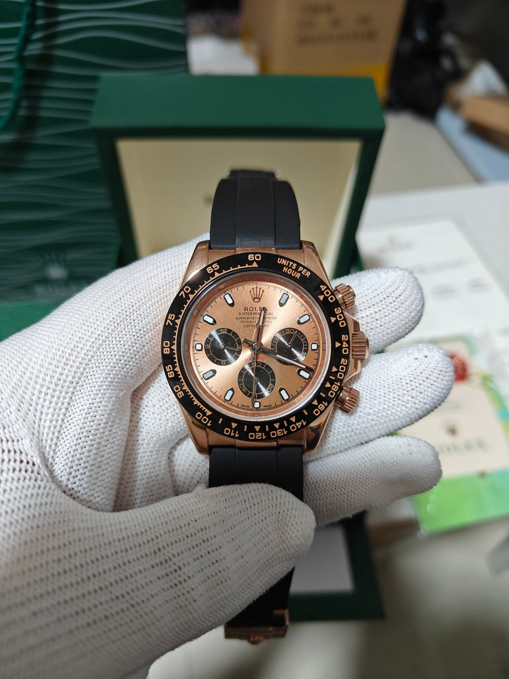 Rolex chronograph watch with black leather strap, rose-gold case, dark dial and 3 subdials