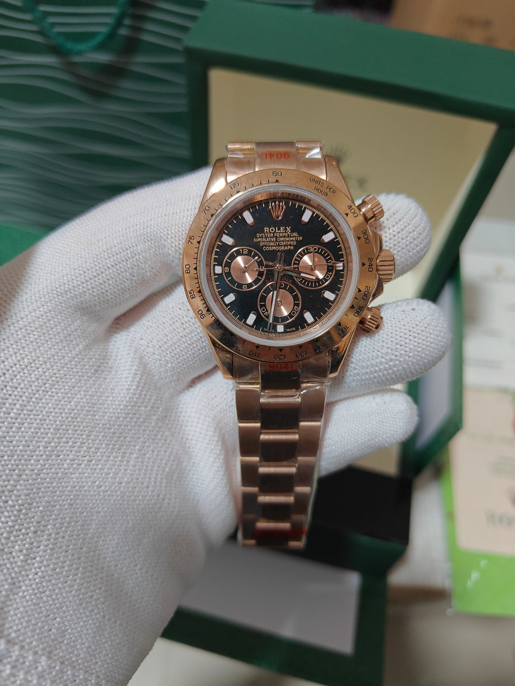 Rolex watch with rose-gold tone case, black dial, and metal link bracelet