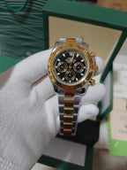 Rolex watch with gold-tone bezel, black dial, three subdials and crown at 3