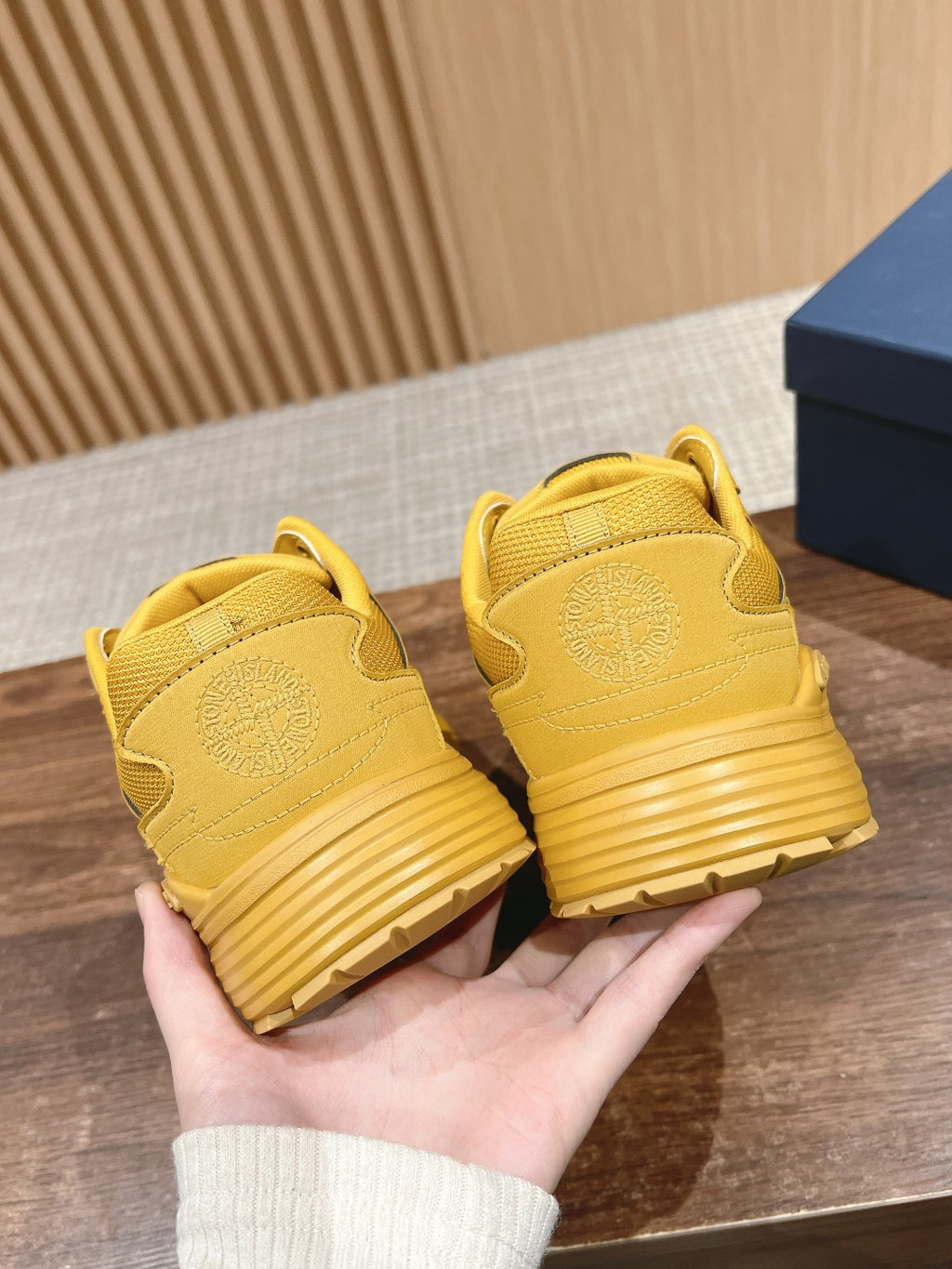 Back view of yellow sneakers with ribbed sole and Dior logo on heel tabs
