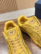 Pair of yellow Dior unisex lace-up sneakers with logo tongue labels