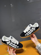 Black low-top sneaker with white geometric panels, lace-up front, gum sole