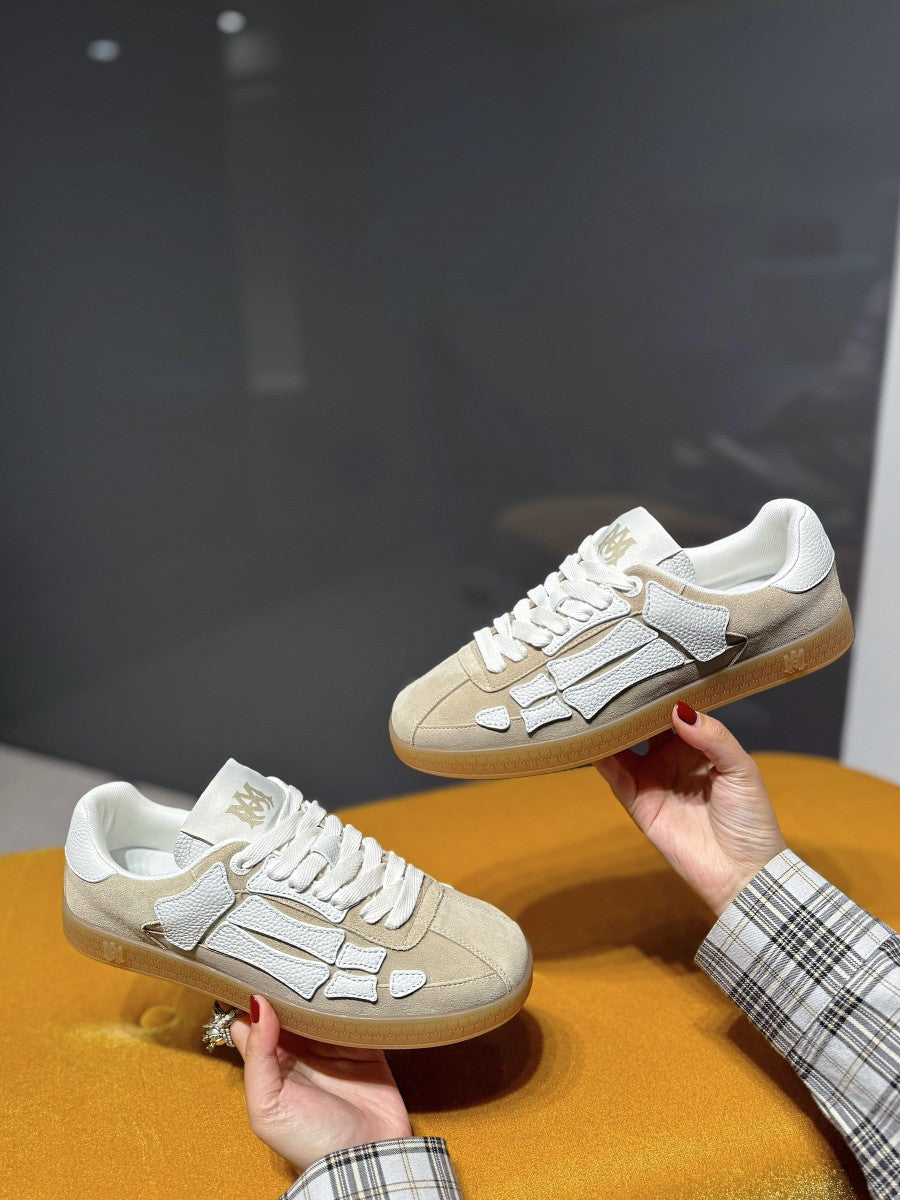 Amiri cream lace-up sneakers with gray logo panels, shown as a pair