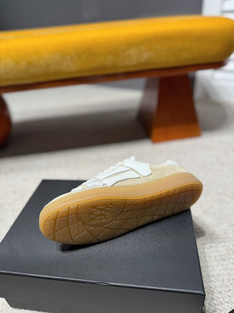 Amiri cream low-top sneakers shown from the outsole side, gum tread