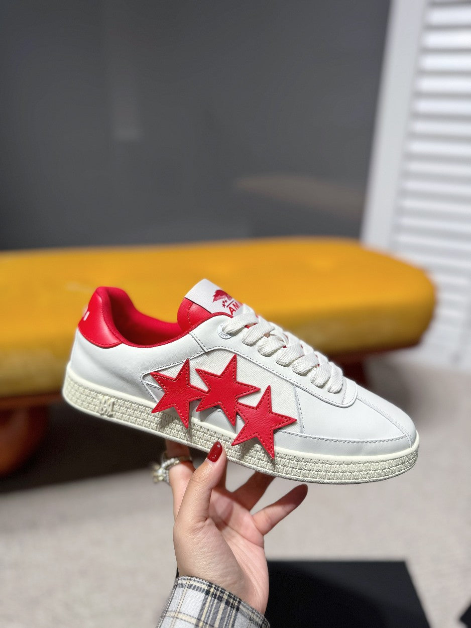 White low-top sneakers with red four-star motif and red interior lining