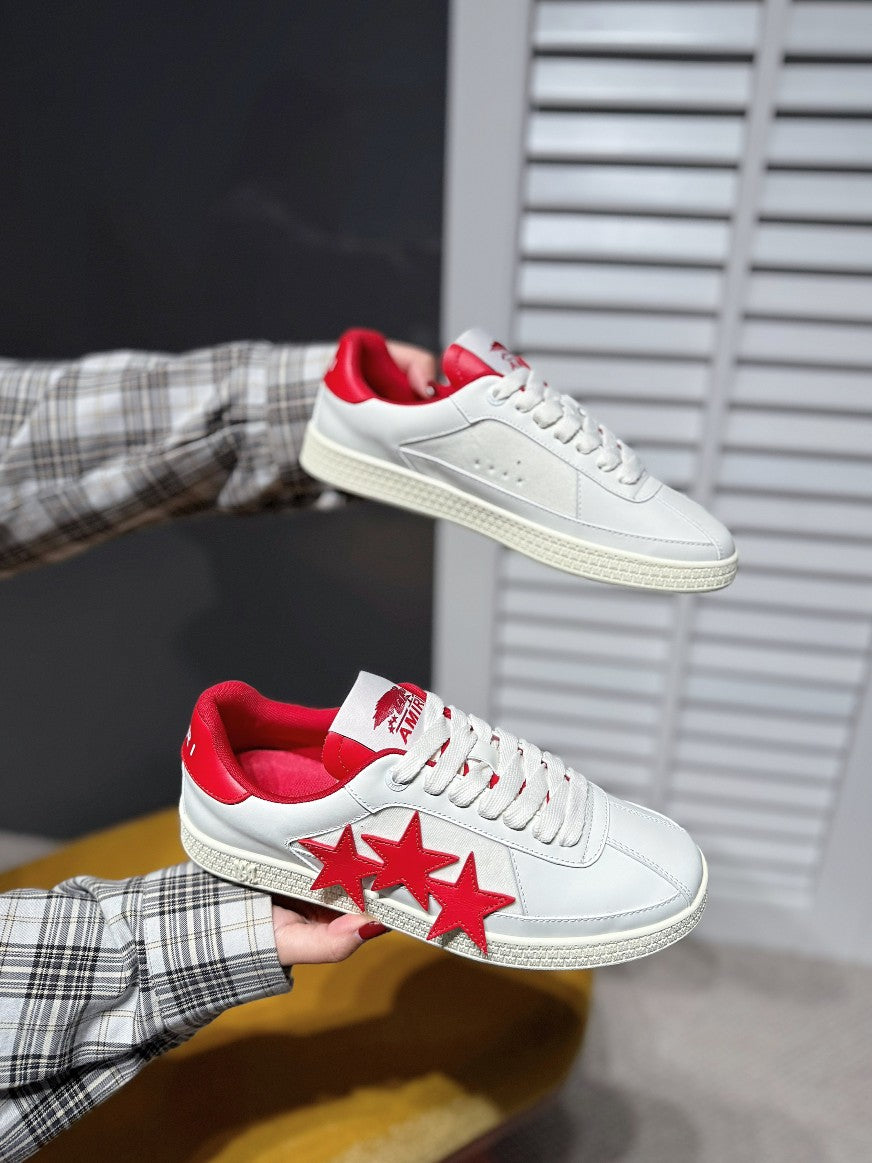 White low-top sneakers with red three-star side graphic and red heel lining