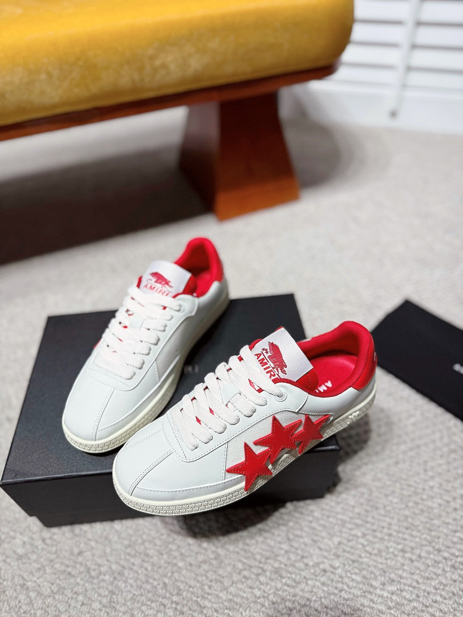 Pair of white low-top sneakers with red star detail and red interior lining