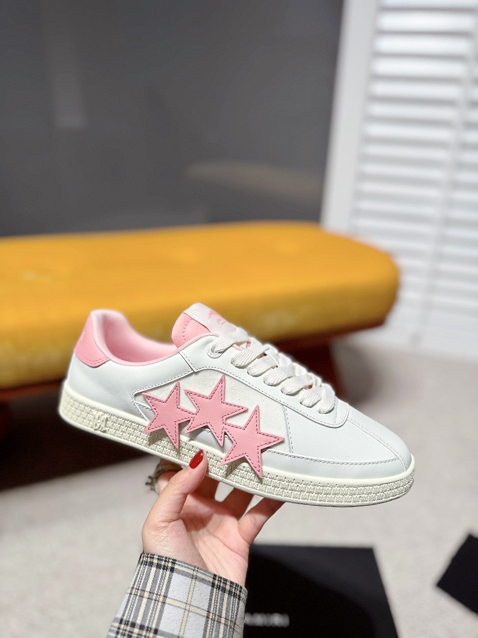 White sneaker with pink triple-star applique, lace-up front, and pink collar
