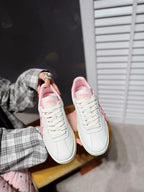 Pair of white lace-up sneakers with pink interior and cushioned collar