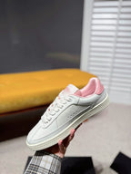 White low-top sneaker with silver-toned sole edge and pink lining at heel