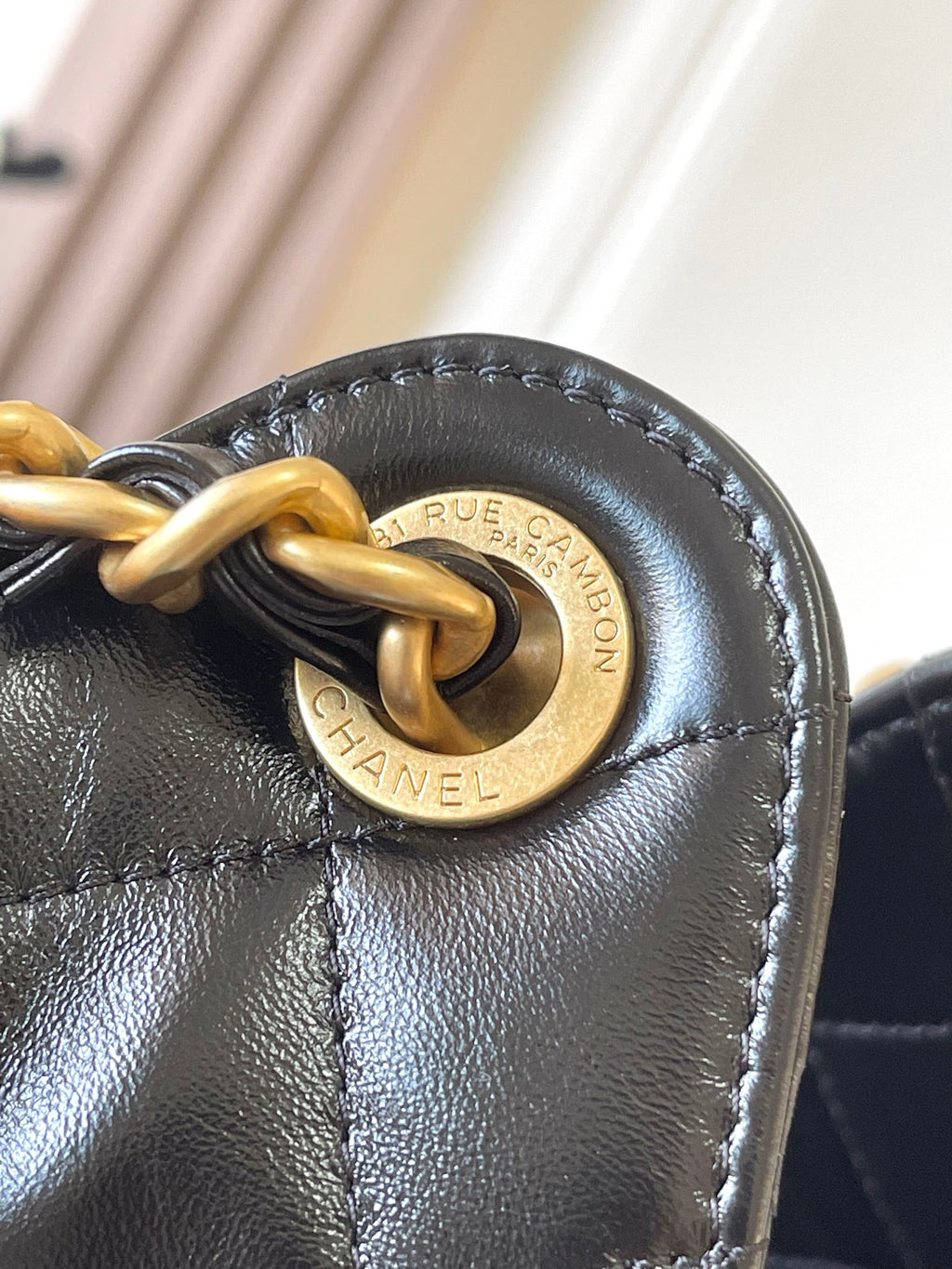 Chanel round gold logo plaque on black leather with chain ring